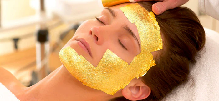 mujer recibiendo tratamiento facial de 24 kilates con mascarilla de oro aplicada en rostro para rejuvenecimiento y luminosidad premium