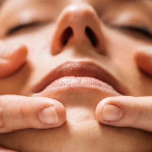 Masaje facial en mujer con técnicas profesionales para rejuvenecimiento y relajación