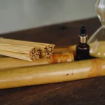 cañas de bambú sobre mesa de madera con aceite esencial y reloj de arena para sesión de bambuterapia