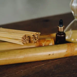 cañas de bambú sobre mesa de madera con aceite esencial y reloj de arena para sesión de bambuterapia