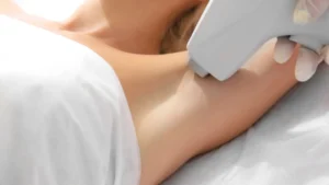 esteticista aplicando depilación láser en brazo de mujer con equipo profesional para eliminación permanente del vello corporal