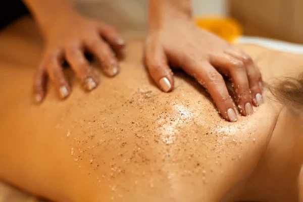 aplicación de peeling corporal con gránulos exfoliantes en la espalda para eliminar células muertas y renovar la piel