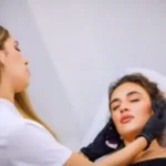 esteticista consultando con clienta sobre tratamiento remodelante corporal mirando resultados o planificación en espejo de centro estético