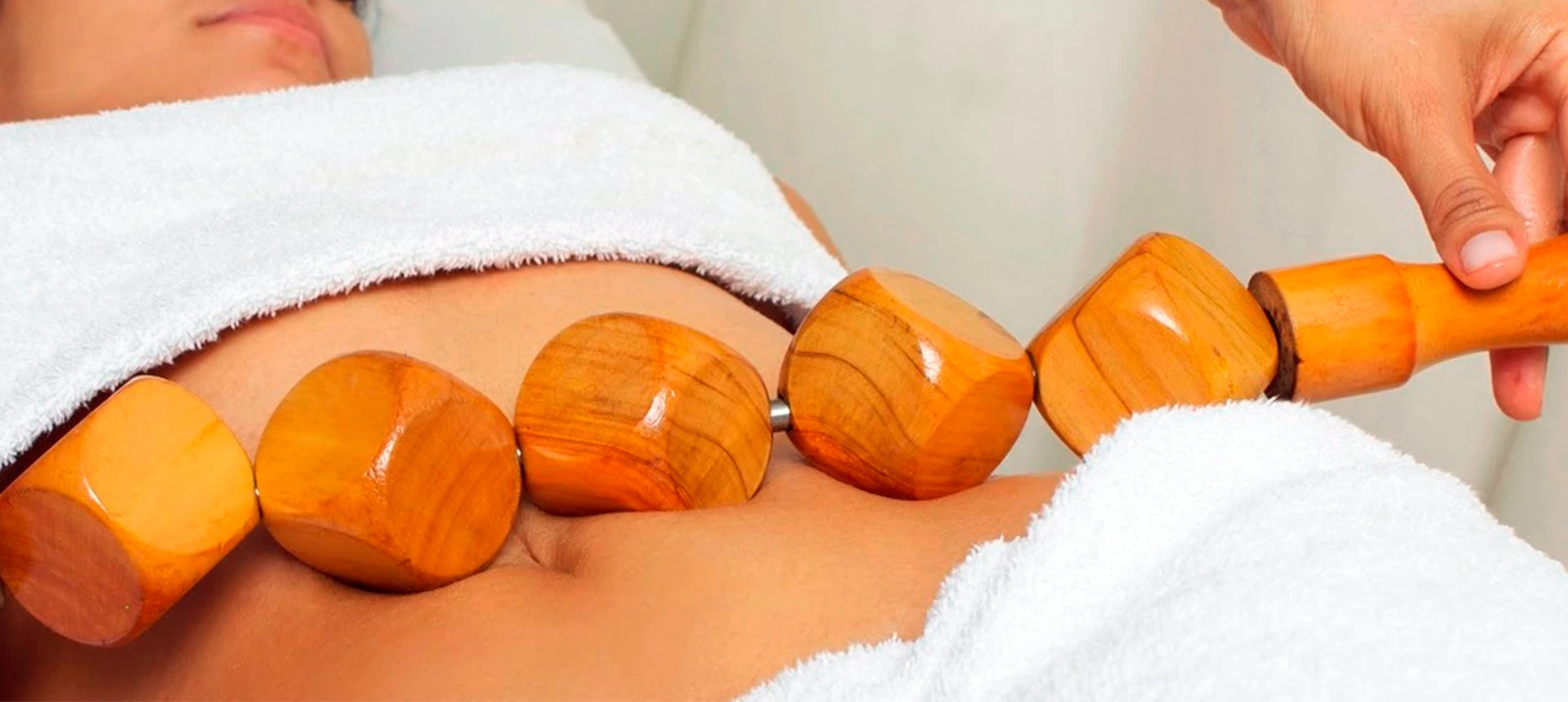 sesión de maderoterapia con rodillos de madera aplicados en piernas para tratamiento reductor y anticelulítico
