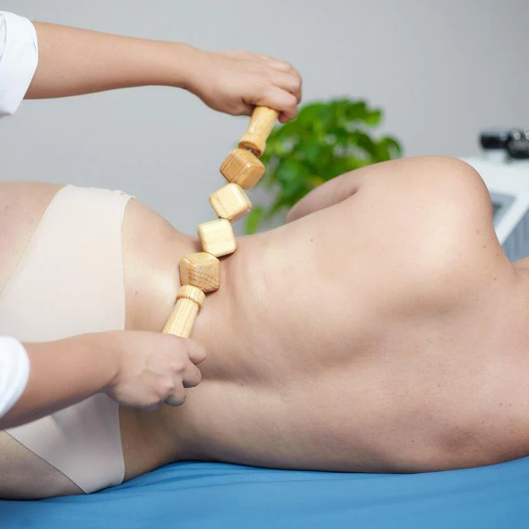 terapeuta aplicando maderoterapia con rodillo de madera en abdomen y piernas para tratamiento reductor y anticelulítico