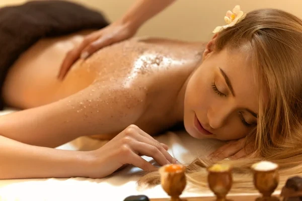 mujer relajada recibiendo peeling corporal en spa con expresión de bienestar y tranquilidad durante el tratamiento