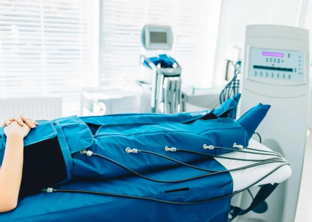 sala de tratamiento de presoterapia equipada con máquina profesional y camilla con botas de compresión azules en centro estético moderno