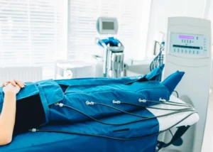 sala de tratamiento de presoterapia equipada con máquina profesional y camilla con botas de compresión azules en centro estético moderno