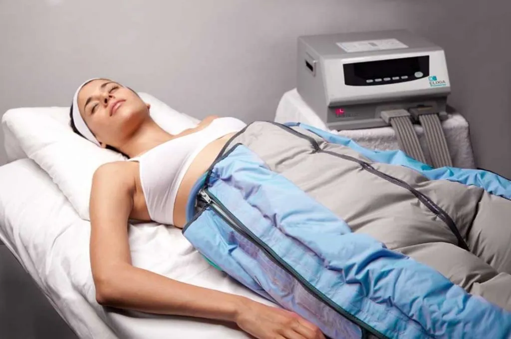 mujer relajada recibiendo tratamiento remodelante corporal con presoterapia en piernas usando botas de compresión azules en centro estético
