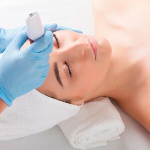 esteticista realizando tratamiento de mesoterapia inyectable en mano de paciente con guantes azules en centro estético profesional