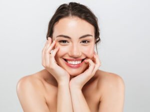 mujer sonriente con piel facial radiante y saludable mostrando resultado de tratamiento estético facial