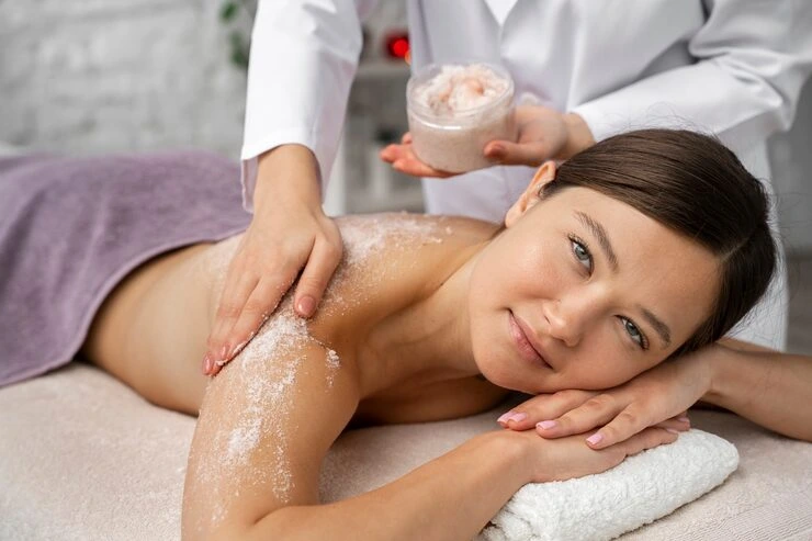 mujer relajada recibiendo tratamiento de peeling corporal en camilla de spa con ambiente tranquilo y profesional